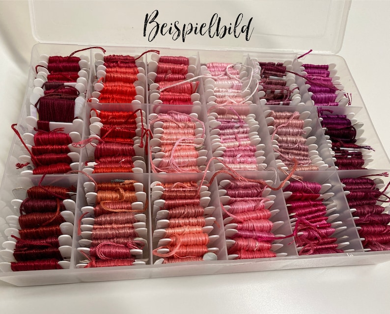 May include: A clear plastic organizer filled with spools of embroidery floss in various shades of red, pink, and purple. The floss is neatly arranged in individual compartments, with the text "Beispielbild" in the top center.