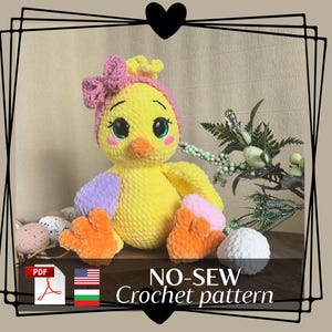 May include: A handmade yellow crochet chick with a pink bow and headband, purple and pink accents, and orange feet. The chick is sitting on a wooden surface with decorative eggs and greenery. The text "NO-SEW Crochet pattern" is visible.