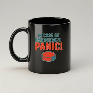 May include: Black ceramic mug with the text "IN CASE OF EMERGENCY, PANIC!" in teal and red. A red and blue hockey puck graphic is below the text. The mug has a curved handle.