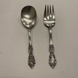 Puede incluir: Un juego de cubiertos de plata plateada, que incluye una cuchara y un tenedor, con diseños florales ornamentados en los mangos.