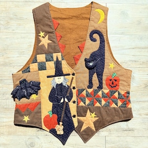 May include: A sleeveless vest featuring a patchwork design with Halloween motifs including a witch with a broom, a black cat, a bat, a jack-o'-lantern, stars, and a crescent moon. The garment uses brown, orange, and black fabrics with various patterns.