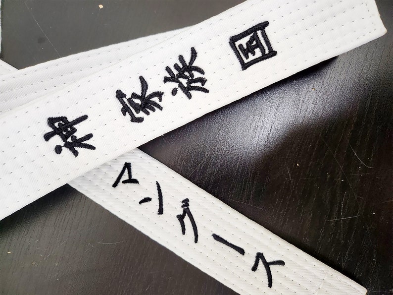 May include: White martial arts belt with black embroidered text that reads "Black Belt" and "A-1 Karate".
