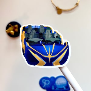 May include: A blue and gold roller coaster car sticker. The car has four seats and is designed to look like a futuristic vehicle.