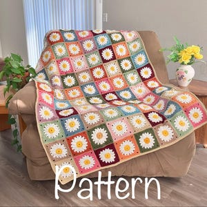 May include: A colorful crochet blanket draped over a chair. The blanket features a daisy pattern with white petals and yellow centers, set against various pastel-colored squares. The word "Pattern" is written across the bottom.