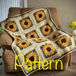 May include: A crocheted blanket featuring a sunflower pattern. The blanket is made of beige yarn with yellow and dark brown sunflowers. The sunflowers are framed by green squares. The word "Pattern" is written in yellow across the blanket.