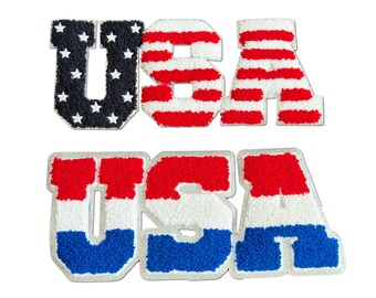 May include: Two embroidered patches spelling out "USA" in large, bold letters. The top patch features the American flag with red and white stripes and blue stars. The bottom patch features the American flag colors in a vertical stripe pattern: red, white, and blue.