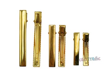 May include: A collection of six gold-colored metal hair clips in various sizes. The clips are arranged vertically, showcasing their rectangular and textured designs. The clips are designed to hold hair in place.