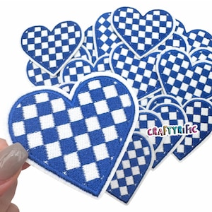 May include: A pile of blue and white checkered heart-shaped iron-on patches. The patches are approximately 2 inches in diameter. The patches are perfect for adding a touch of personality to clothing, bags, and other accessories.