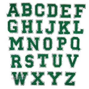 May include: A set of 26 iron-on letters in a green felt fabric with a silver glitter outline. The letters are uppercase and are arranged in alphabetical order.