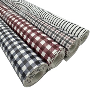 May include: Four rolls of patterned faux leather fabric. The patterns include black and white stripes, plaid, and gingham in shades of gray, burgundy, and black. The rolls are tightly wound and ready for crafting projects.