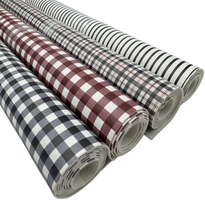May include: Four rolls of patterned faux leather fabric. The patterns include black and white stripes, plaid, and gingham in shades of gray, burgundy, and black. The rolls are tightly wound and ready for crafting projects.