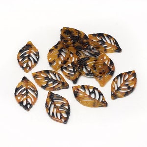 May include: A group of brown and black tortoise shell leaf-shaped charms with a cutout design.