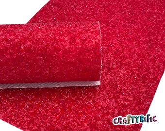 May include: Red glitter fabric sheet. The fabric is a sparkly red color with a fine glitter texture. The sheet is rolled up and the text "CRAFTYRIFIC" is visible in the bottom right corner.