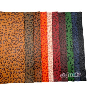 K&ouml;nnte beinhalten: Sortiment aus Kunstlederb&ouml;gen in verschiedenen Farben mit einem gepr&auml;gten Leopardenmuster. Die Farben umfassen Braun, Schwarz, Orange, Rosa, Rot, Dunkelrot, Gr&uuml;n und Blau.