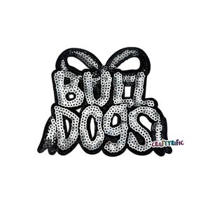 May include: A black and silver sequined patch with the words "BULLDOGS" in a stylized font. The patch has a black border and a bow-like design at the top. The text "CRAFTYRIFIC" is in the lower right corner.
