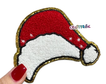 May include: Red and white felt Santa hat patch with gold glitter trim. The patch has a white pom-pom on the top and is outlined in gold glitter.