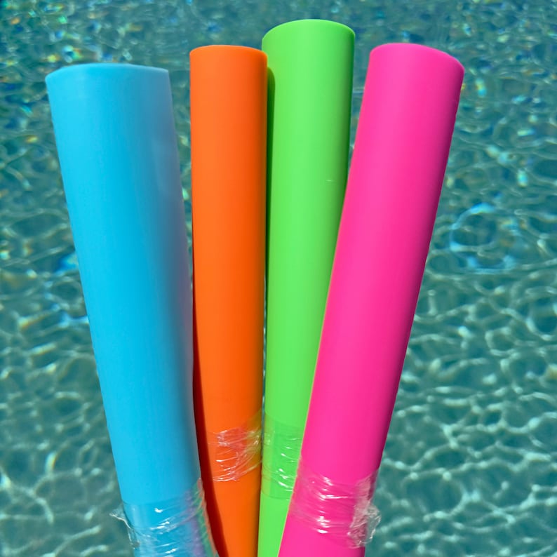 May include: Four pool noodles in different colors: blue, orange, green, and pink. The noodles are wrapped in plastic and are floating in a swimming pool.
