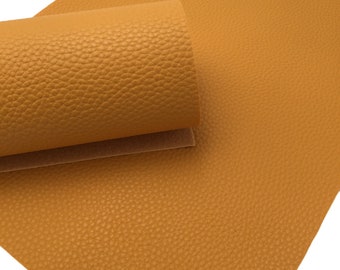 May include: A sheet of mustard yellow faux leather with a textured, pebbled surface. The leather is rolled up, showing the texture.