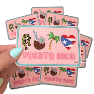 May include: A set of eight pink embroidered iron-on patches featuring a green frog playing a ukulele, a coconut with a straw, a palm tree, and a red, white, and blue heart with a star in the center. The patches say "PUERTO RICO" in white text.