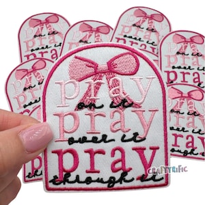 May include: A set of pink and white iron-on patches with the text "Pray on it, pray over it, pray through it" and a pink bow.