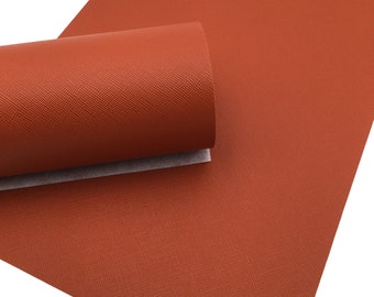 May include: A close-up of a sheet of burnt orange faux leather with a textured surface. The leather is rolled up, showing the texture.