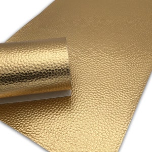 May include: A sheet of gold faux leather with a textured, pebbled surface. The leather is rolled up, showing the texture.