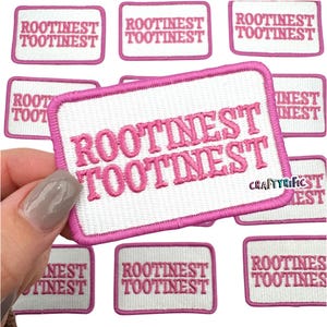 May include: Pink and white embroidered iron-on patch with the text "ROOTINEST TOOTINEST" repeated twice.