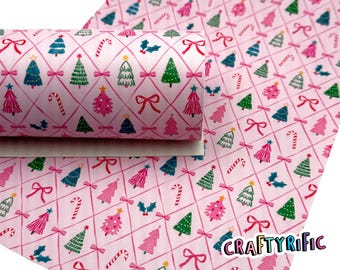 May include: Pink Christmas-themed faux leather sheet with a repeating pattern of Christmas trees, bows, candy canes, and holly. The trees are in shades of pink, green, and blue, set against a grid of pink lines. The CraftyRific logo is visible.