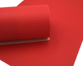 May include: A sheet of red faux leather with a textured surface. The leather is rolled up and the texture is visible.