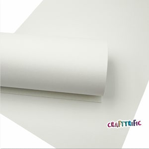 May include: A roll of white faux leather with a textured surface. The leather is rolled up and the end is visible. The text "CRAFTYRIFIC" is printed in rainbow colors on the bottom right corner of the image.