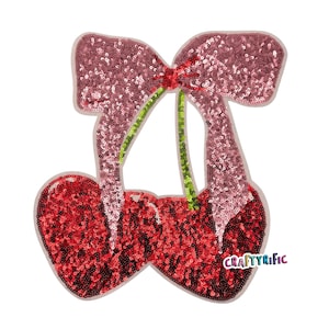 May include: A red and pink sequined cherry with a pink bow. The cherry is a fabric applique with a Craftyrific label.