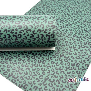 May include: A sheet of green faux leather with a black leopard print pattern. The leather is rolled up and the pattern is visible on both the rolled and unrolled portions.