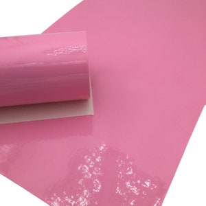 May include: A roll of pink faux leather with a glossy finish. The leather is rolled up and the end is visible.