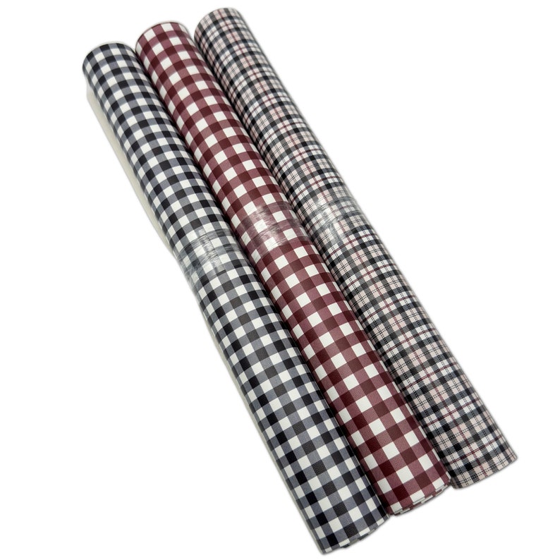 May include: Three rolls of patterned wrapping paper. The rolls feature a black and white gingham pattern, a burgundy and white gingham pattern, and a black, red, and white plaid pattern. The rolls are wrapped in clear plastic.