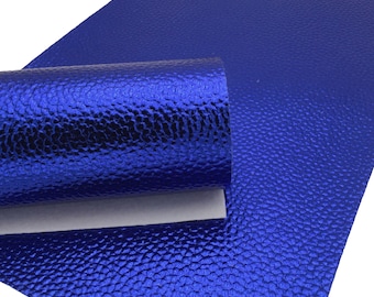 May include: A sheet of vibrant blue faux leather with a textured, pebbled surface. The material is partially rolled, revealing a white backing. The shiny, metallic-like finish gives it a luxurious appearance, suitable for various crafting projects.
