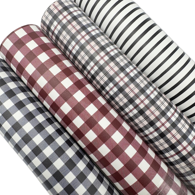 May include: Four rolls of patterned faux leather in various designs. The patterns include gray and white gingham, burgundy and white gingham, black and white plaid, and black and white stripes. The rolls are tightly wound and ready for crafting.