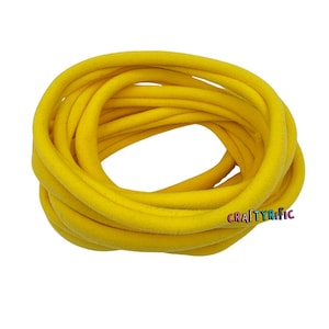 May include: A close-up of a large spool of bright yellow elastic hair ties. The hair ties are made of a soft, stretchy material and are perfect for holding hair in place.