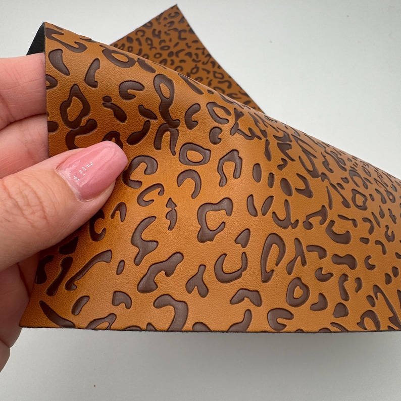 K&ouml;nnte beinhalten: Ein Blatt braunes Kunstleder mit einem dunkelbraunen, gepr&auml;gten Leopardenmuster.