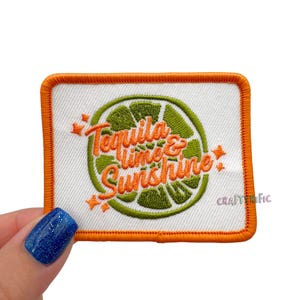 May include: Embroidered patch with an orange border and the words "Tequila, Lime & Sunshine" in orange script. The design includes a green lime slice. The patch is rectangular and has the text "CRAFTERFIC" in the bottom right corner.