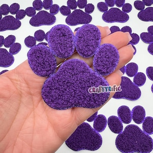 May include: Purple fuzzy paw print fabric patches with a glittery outline. The patches are approximately 2 inches in diameter.
