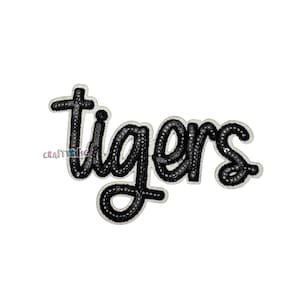 May include: Black sequin iron-on patch with the word "tigers" in a cursive font.