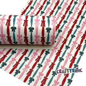 May include: A roll of white patterned material featuring a repeating design of red, pink, and teal ribbons and bows. The material has a diagonal pattern and the text "CRAFTYRIFIC" is visible in the lower right corner.