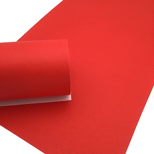 May include: A sheet of bright red faux leather with a textured surface. The leather is rolled up and the edges are visible.