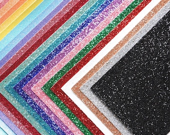 May include: A collection of 24 sheets of glitter paper in various colors, including red, blue, green, pink, purple, orange, yellow, and black. The sheets are arranged in a fan shape, with the black sheet at the bottom.