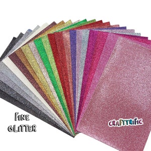 May include: A fan of 20 different colors of fine glitter paper. The paper is a sparkly, textured material. The text "FINE GLITTER" is in the bottom left corner of the image. The text "CRAFTYRIFIC" is in the bottom right corner of the image.