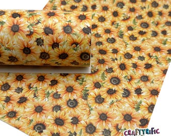 May include: A roll and a sheet of material covered in a repeating pattern of sunflowers. The sunflowers have yellow petals and dark brown centers. The background is a light yellow color. The material is likely for crafting or decorative purposes.