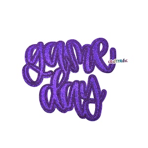 May include: A purple glittery "Game Day" cutout in a cursive font. The text is outlined in a darker purple, creating a 3D effect. The word "CraftyRific" is in the upper right corner.