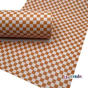 May include: A roll of orange and white checkered patterned material. The material is unrolled on the right side of the image, and rolled up on the left side. The text "CRAFTYRIFIC" is in the bottom right corner.