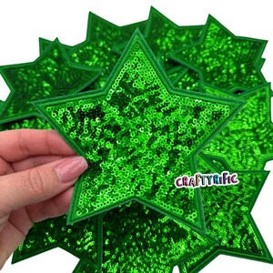 May include: A pack of ten green star-shaped patches with a sparkly sequin finish. The patches are approximately 3 inches in diameter.