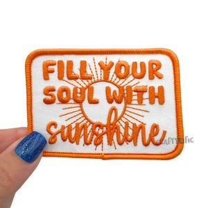 May include: Embroidered patch with the words "FILL YOUR SOUL WITH sunshine" in orange script and block letters. The design includes a sun graphic and an orange border on a white background.